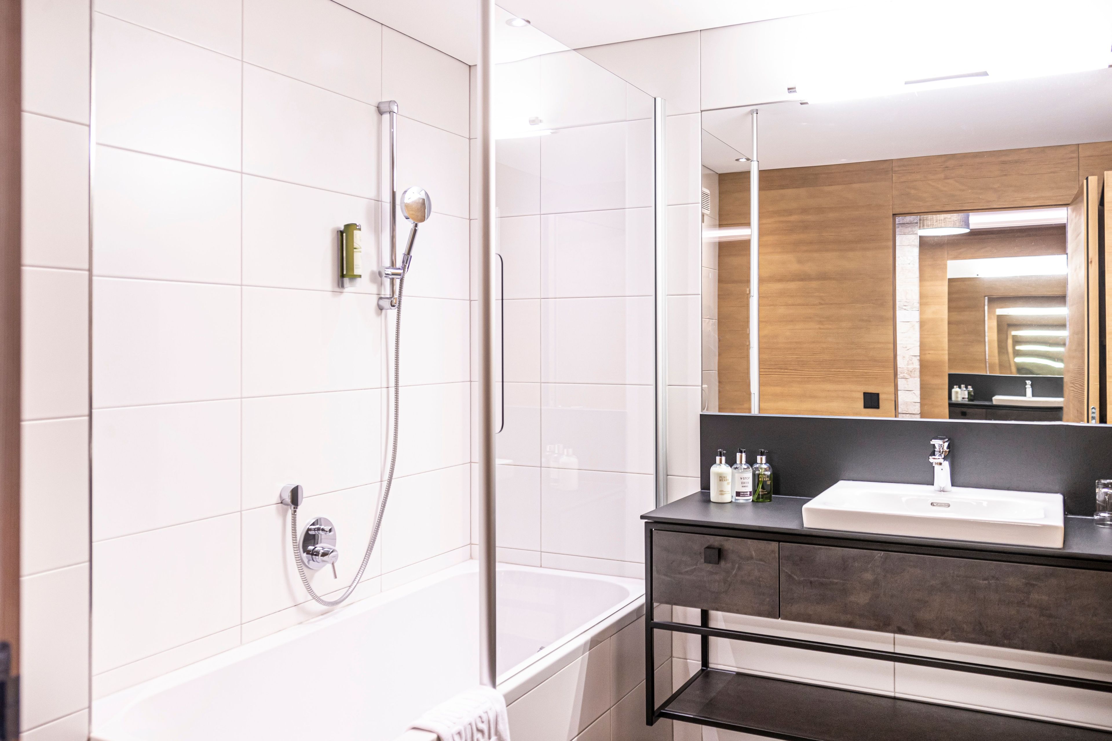 A modern bathroom with a bathtub, a shower, a sink, and a mirror.