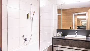 A modern bathroom with a bathtub, a shower, a sink, and a mirror.
