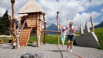 A wooden play structure with climbing elements and a rope bridge.