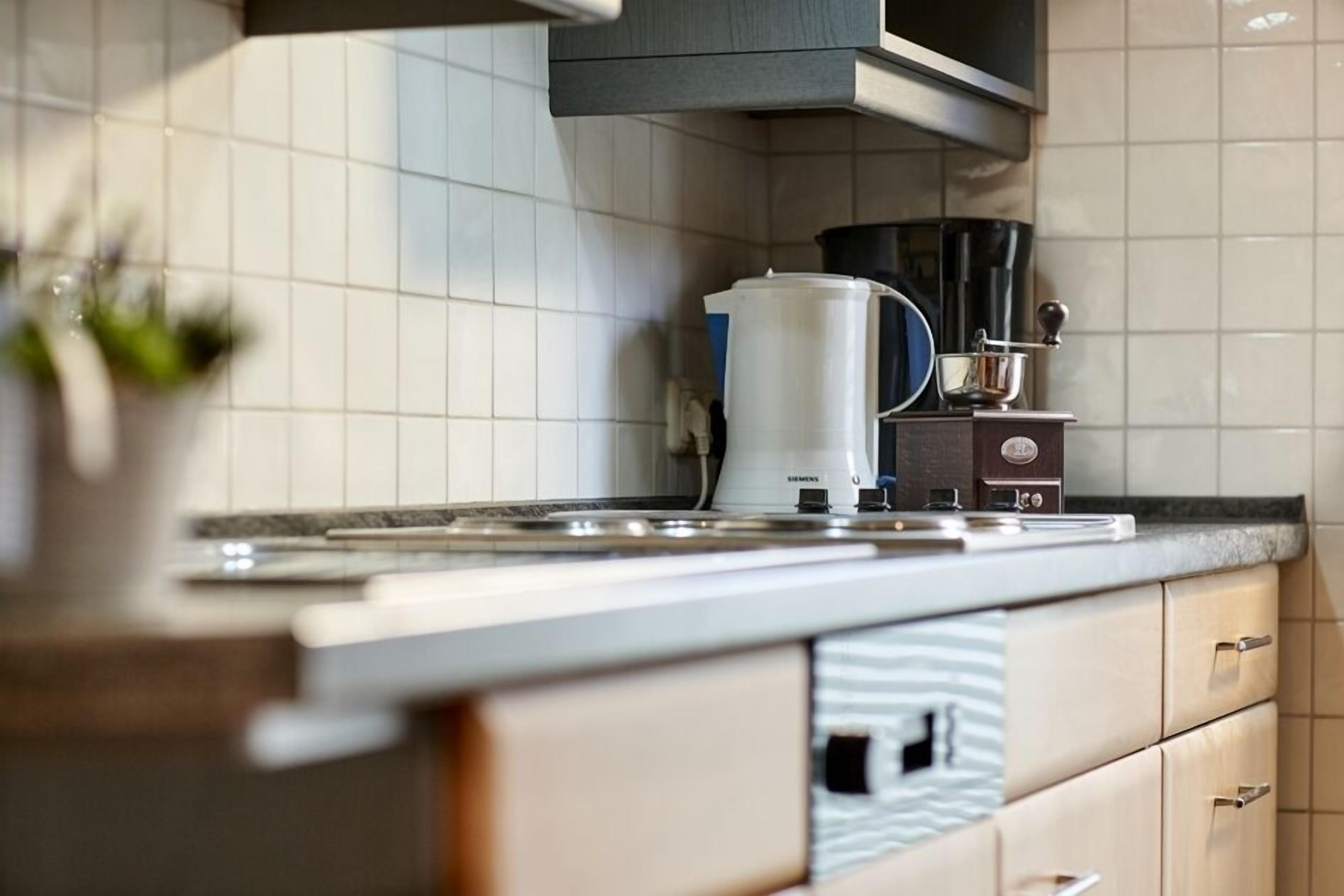 A modern kitchen with white tiles, a coffee maker, and a Siemens appliance.
