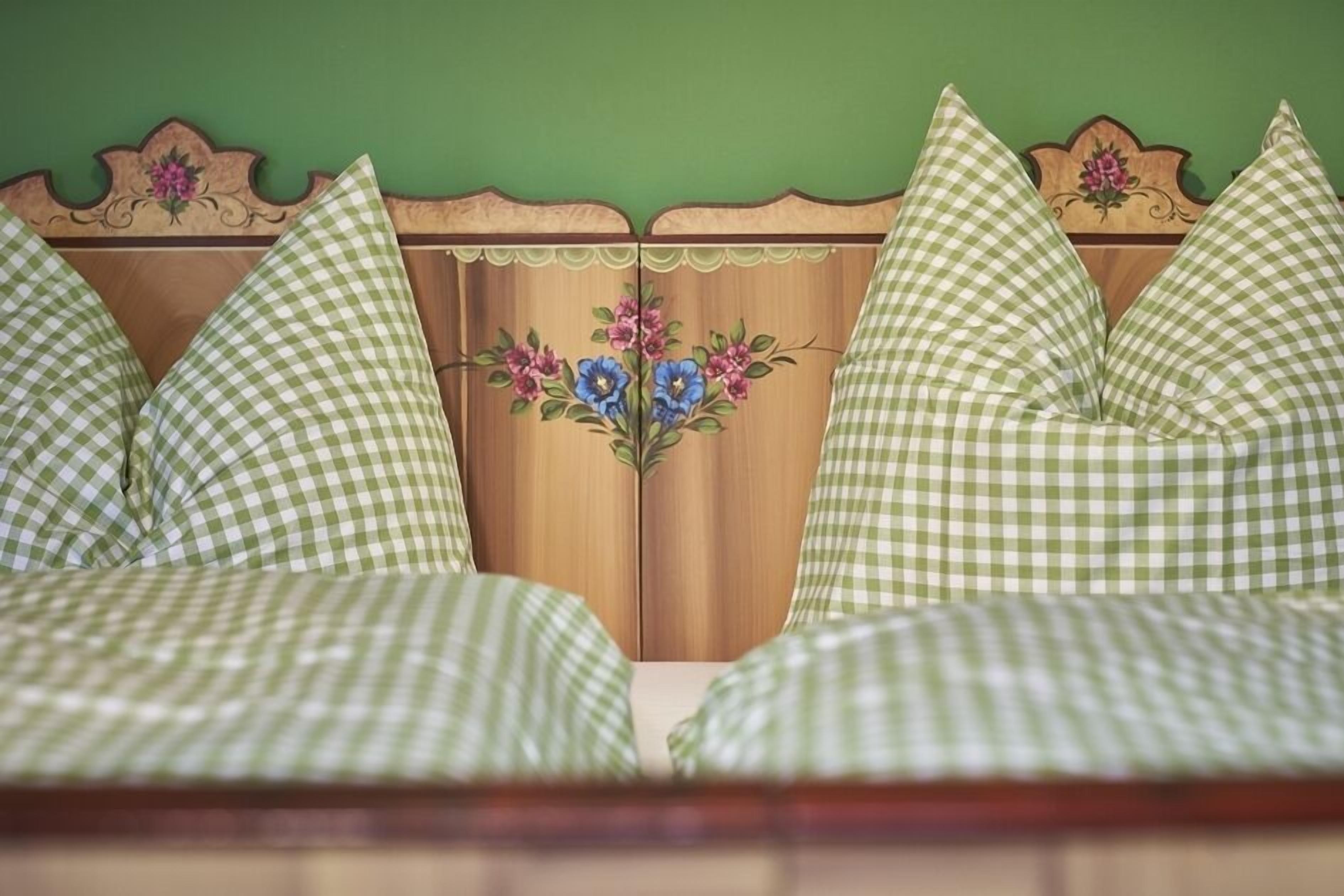 Una cama con ropa de cama verde a cuadros y un cabecero floral.