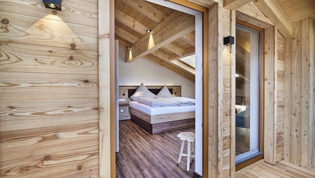 Un intérieur en bois comprenant un lit, des tables de chevet et un tabouret.