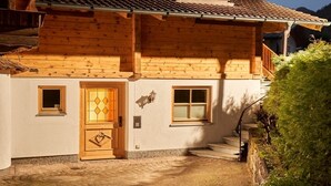 Un chalet en bois avec une porte en bois, deux fenêtres et un escalier menant à un balcon.