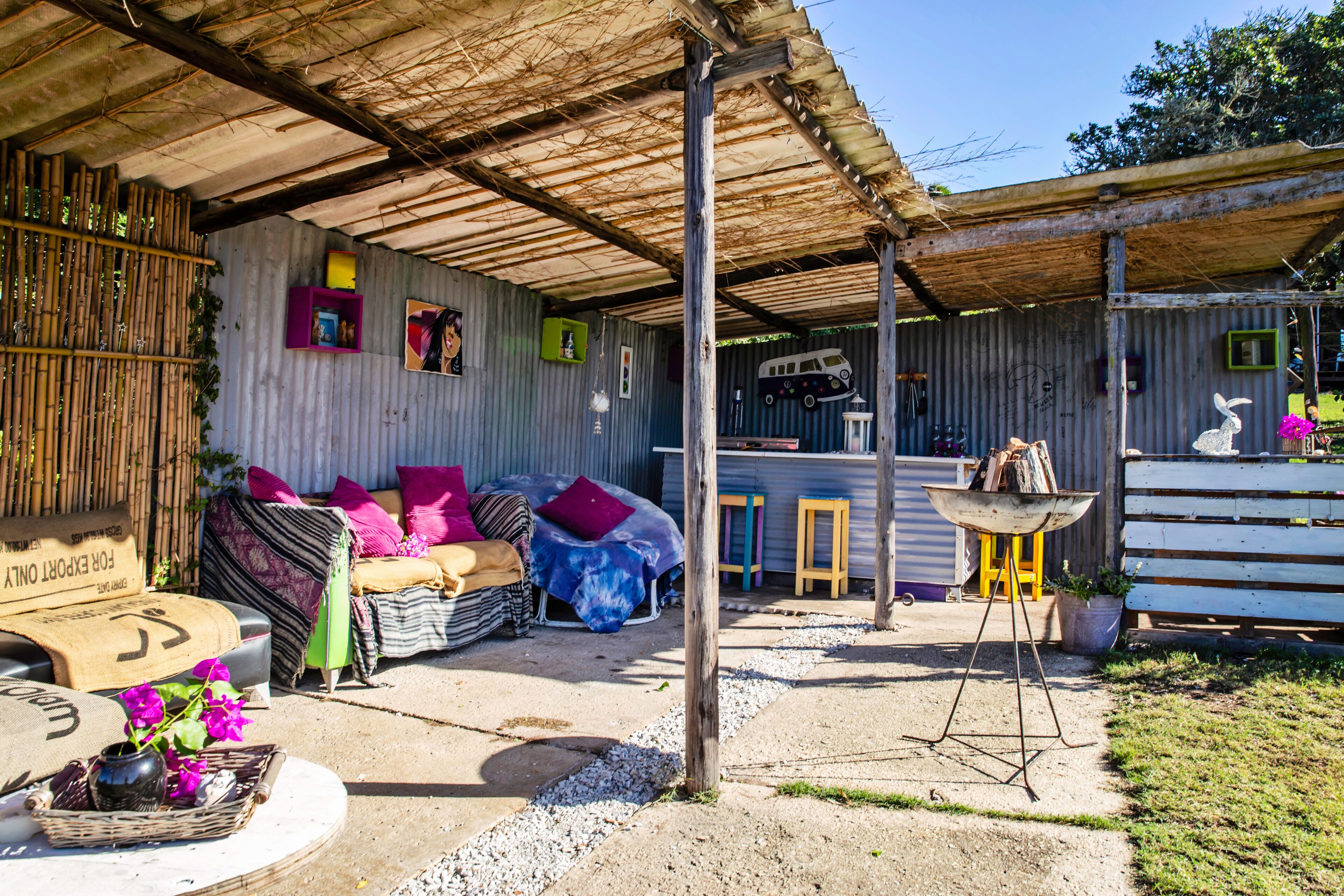 A rustic outdoor seating area with a covered patio, a wooden table, and a decorative rabbit statue.