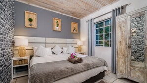 Une chambre à coucher avec un lit, des lampes de chevet, une fenêtre et un mur en pierre.