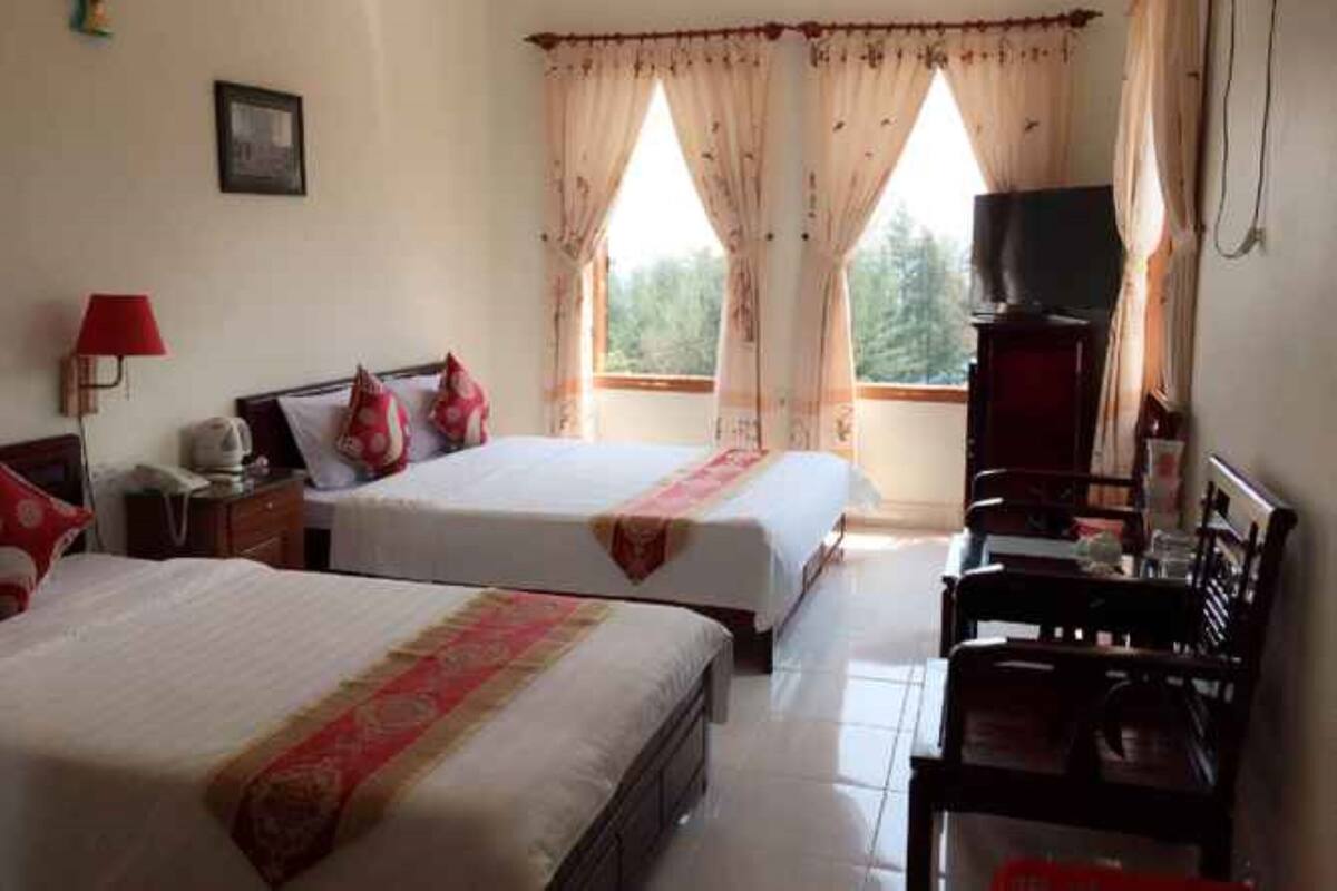 A hotel room with two beds, a TV, and a desk.