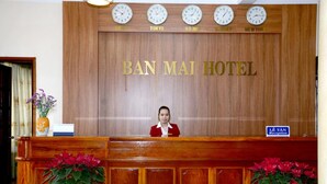 Una mesa de recepción en el HOTEL BAN MAI, con relojes mostrando la hora de Tokio, Hanoi, Sídney y Nueva York.