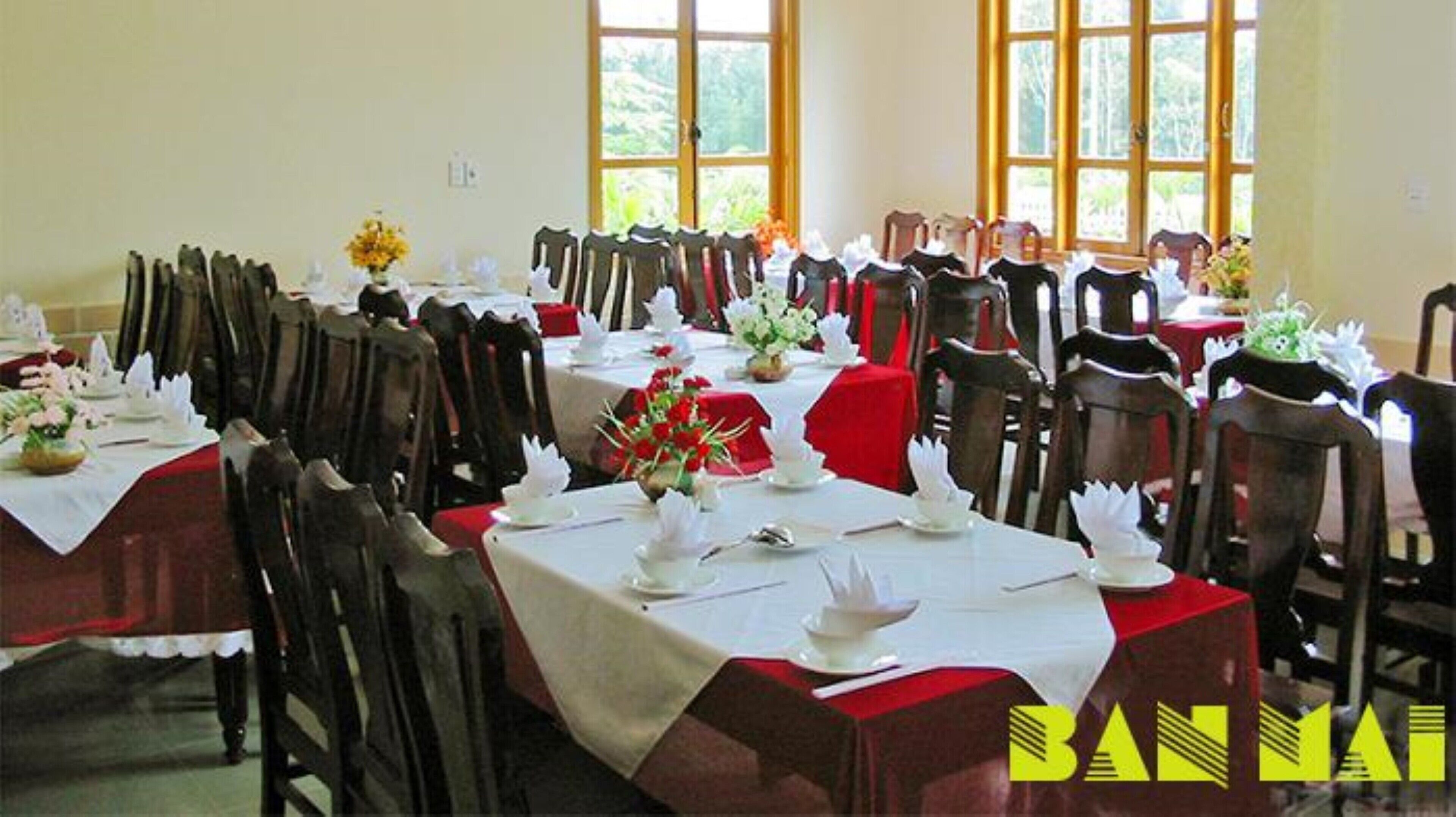 Une salle de banquet avec de nombreuses tables dressées pour le repas, disposées en rangées.