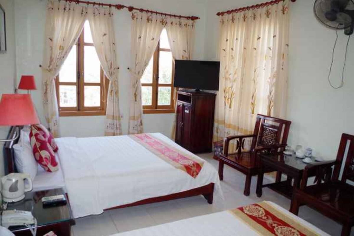 A bedroom with a bed, a TV, a desk with a lamp, and a chair.