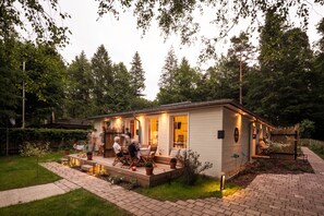A small, single-story house with a patio area. There are several people seated at a table on the patio. - Little Suite Apartments (Dresden)
