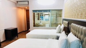 A hotel room with two beds, a small table, a mirror, and a bathroom visible through a glass door. - SeaStar Hotel Ha Long (Bai Chay)