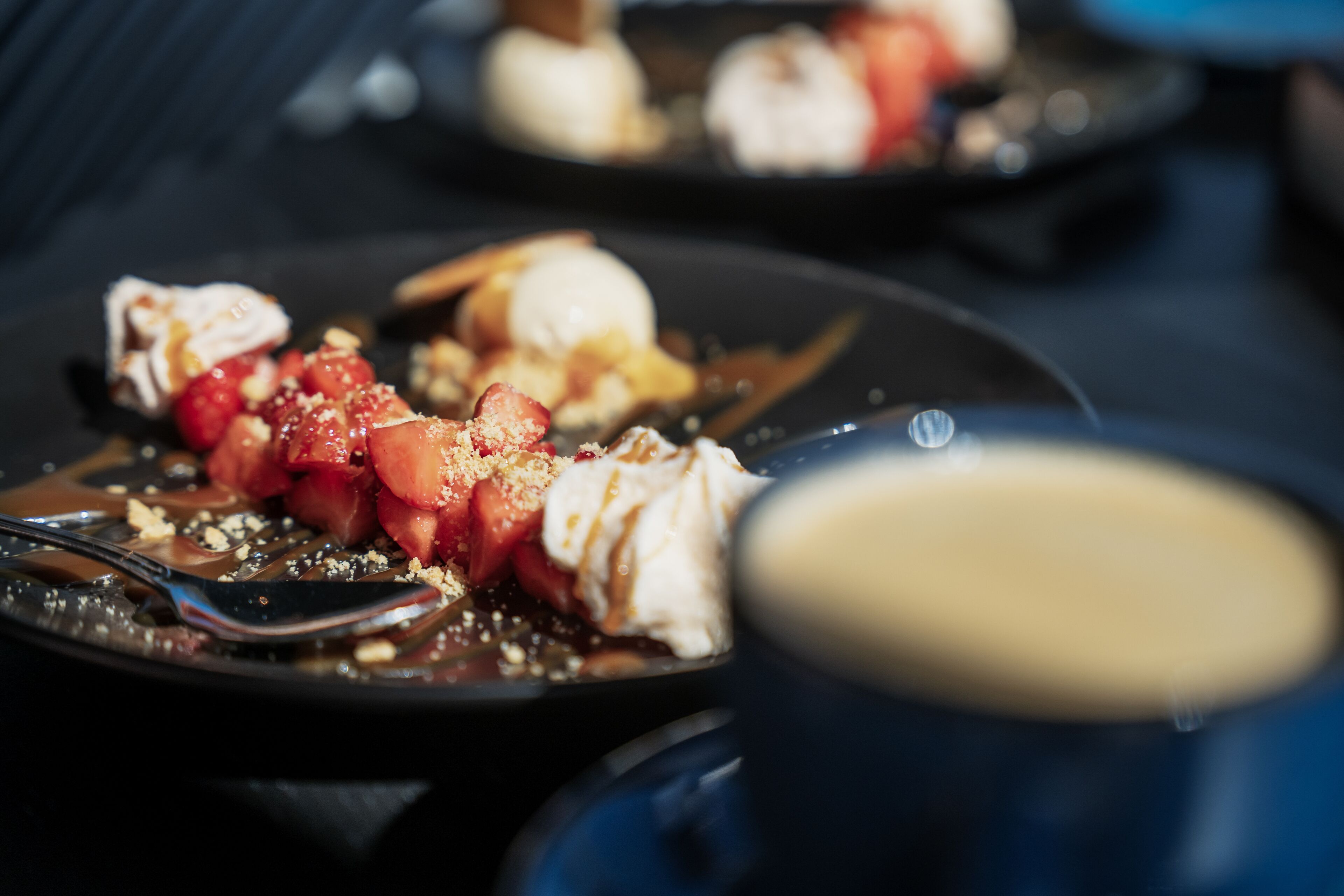 A dessert plate with strawberries, whipped cream, and chocolate sauce.