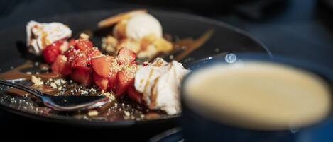 Un plato de postre con fresas, crema batida y salsa de chocolate.