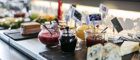 A buffet with various food items including jars of jams, a bowl of soup, and cheese.