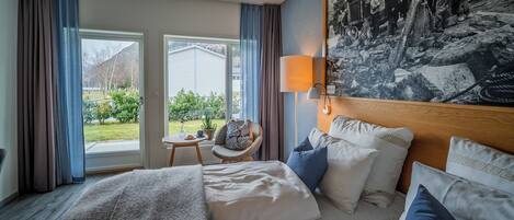 A hotel room with a large bed, a chair, a table, and a view of the outdoors.
