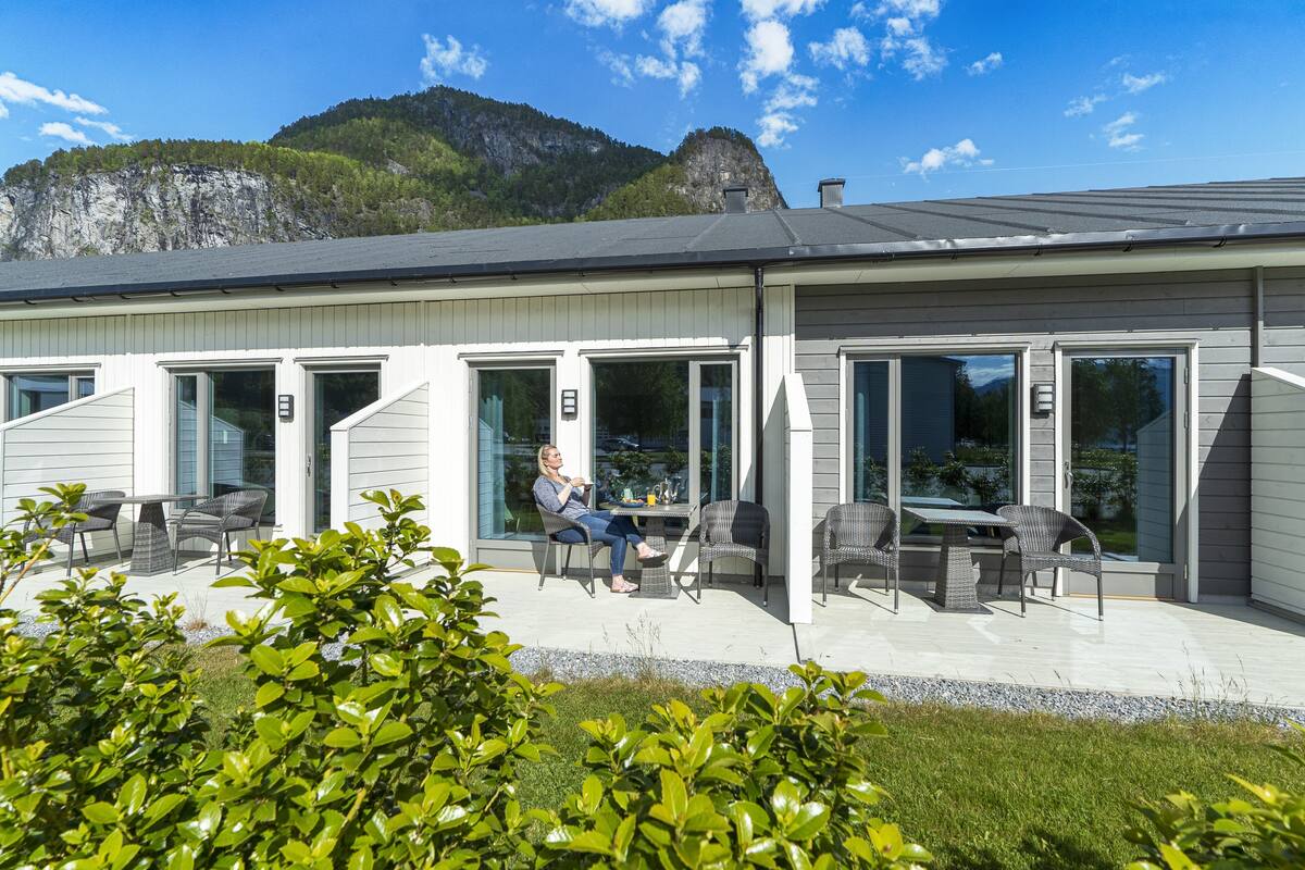 Ein Gebäude mit einer Terrasse, Sitzgelegenheiten im Freien und Blick auf einen Berg.