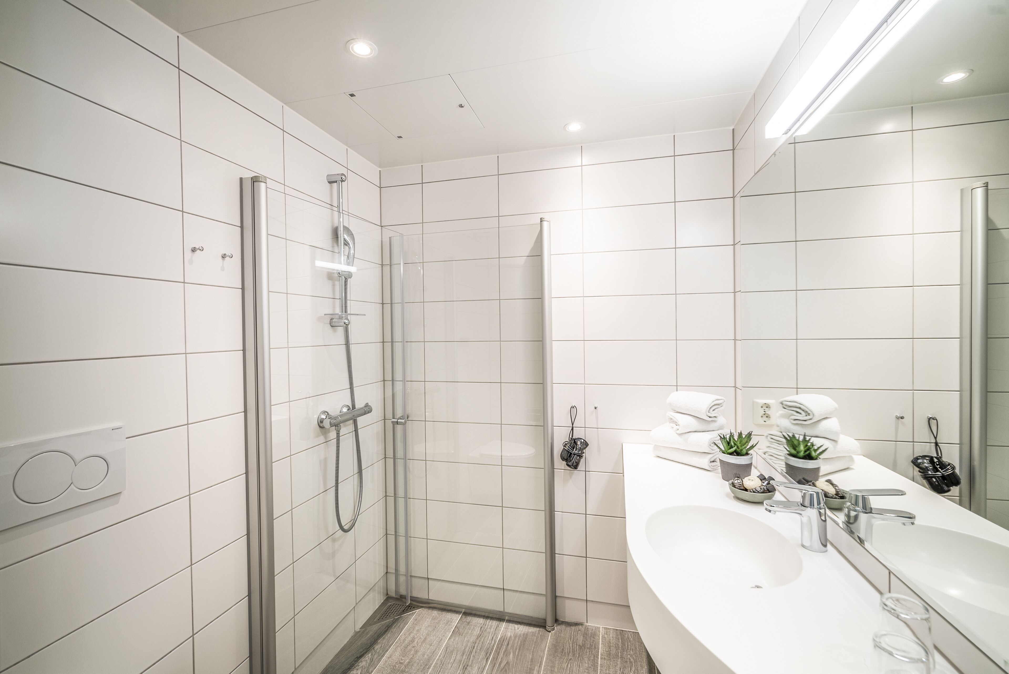 A modern bathroom with a glass-enclosed shower, a large sink, and a mirror.