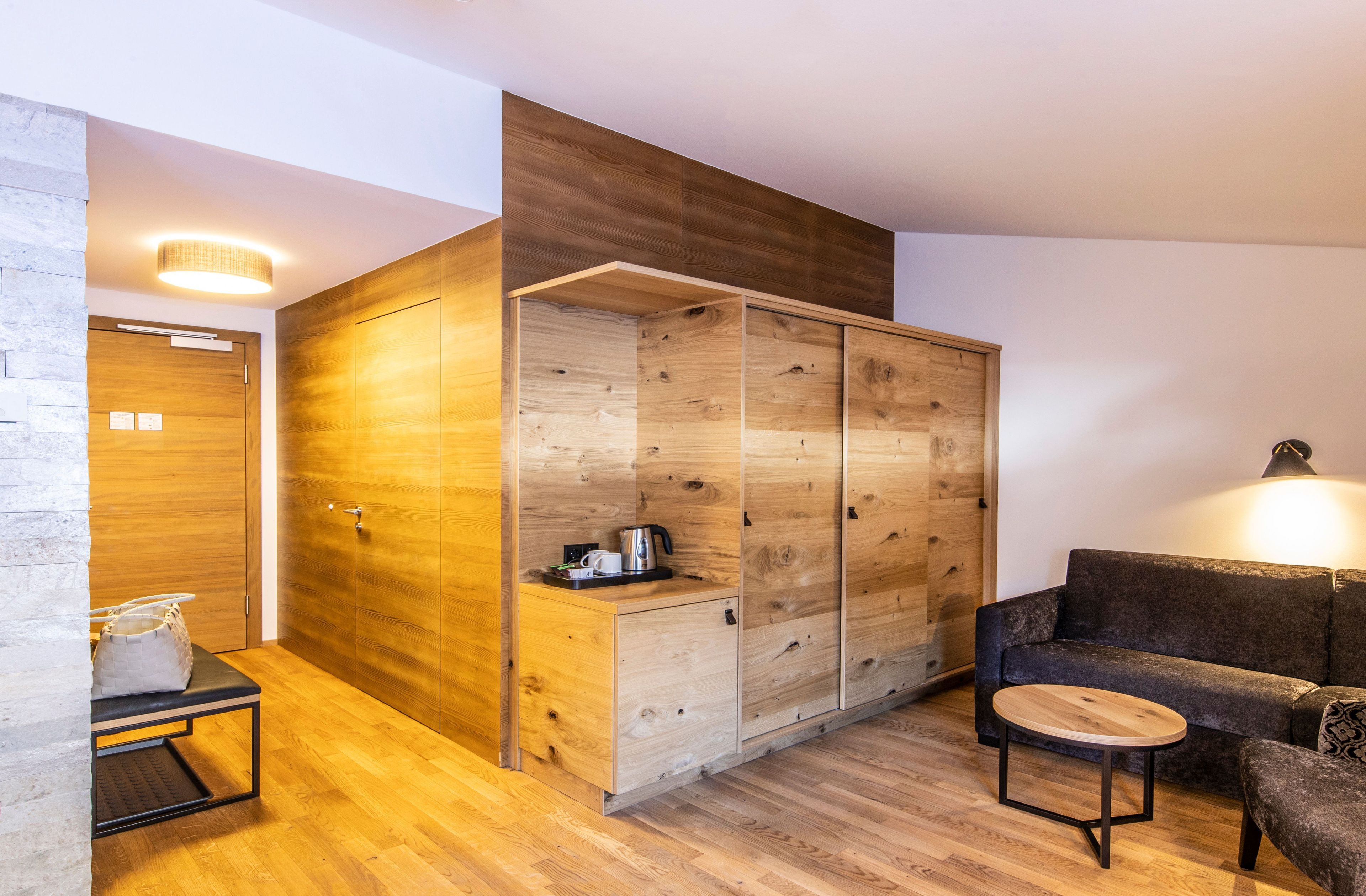 A modern room with a wooden wardrobe, a sofa, a small table, and a bench.