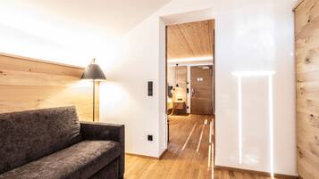 A modern interior with a wooden floor, a grey sofa, and a lamp.
