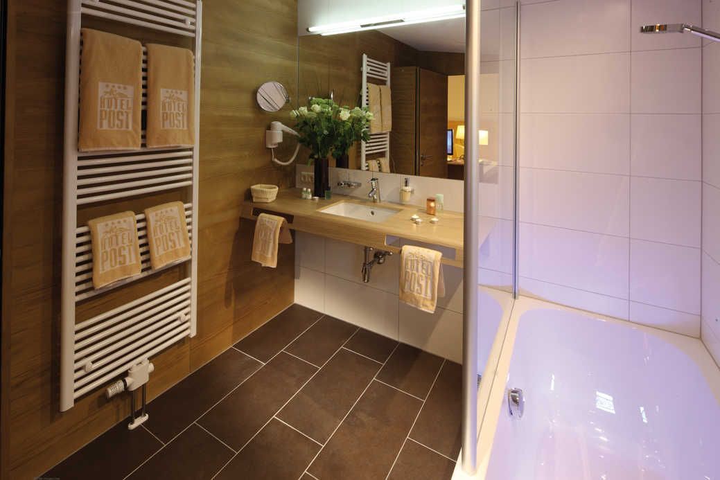 Une salle de bain moderne équipée d’une baignoire, d’un lavabo, d’un miroir et de porte-serviettes.