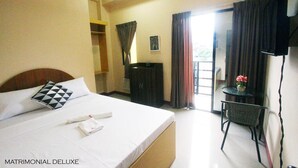 A hotel room with a bed, a desk, a chair, and a television. - Heart Hotel and Services (Dumaguete)
