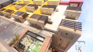 A multi-story hotel with a modern design, featuring balconies with metal railings, a central courtyard with a fountain, and a visible restaurant or cafe at the ground level. - Heart Hotel and Services (Dumaguete)