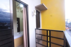 A balcony with a metal railing, a door with a window, and a yellow wall.