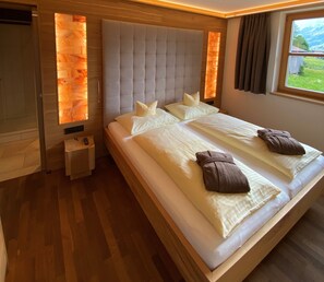 A large bed with a padded headboard, two pillows, and two towels. - Postsuite - Alpen Hotel Post **** (Au)