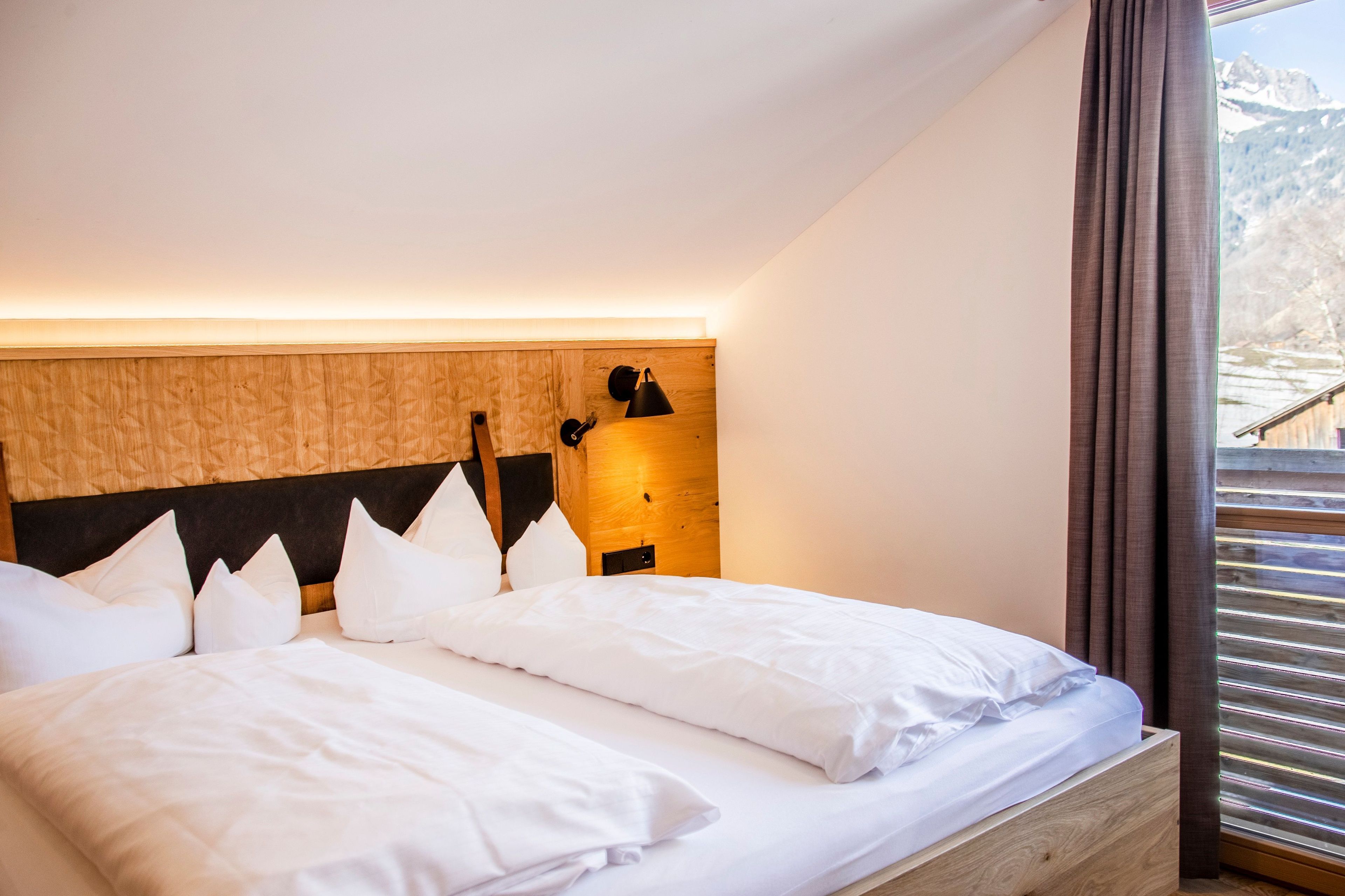 A bedroom with a wooden headboard, a bed with white bedding, a nightstand, and a lamp.