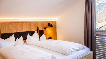 A bedroom with a wooden headboard, a bed with white bedding, a nightstand, and a lamp.
