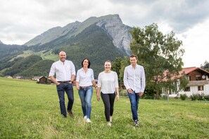 A group of people walking in a grassy field with a mountain in the background. - Postsuite - Alpen Hotel Post **** (Au)