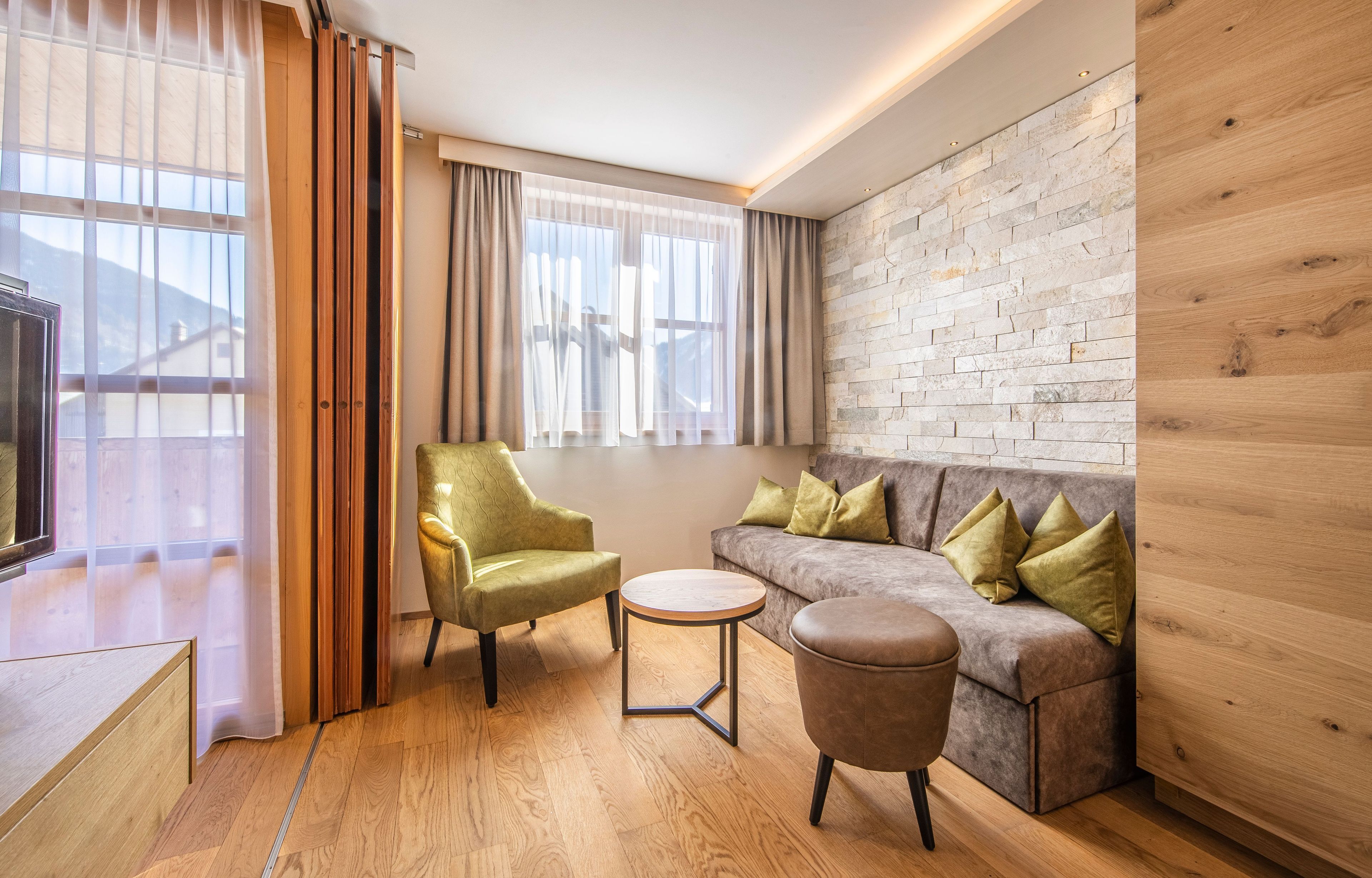 A modern living room with a sofa, armchair, ottoman, and a small round table.
