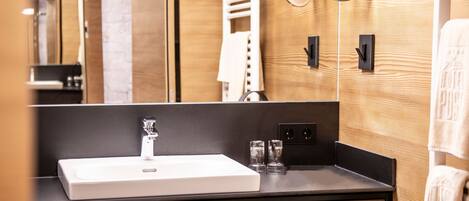 A modern bathroom with a large mirror, a white sink, and a towel rack.