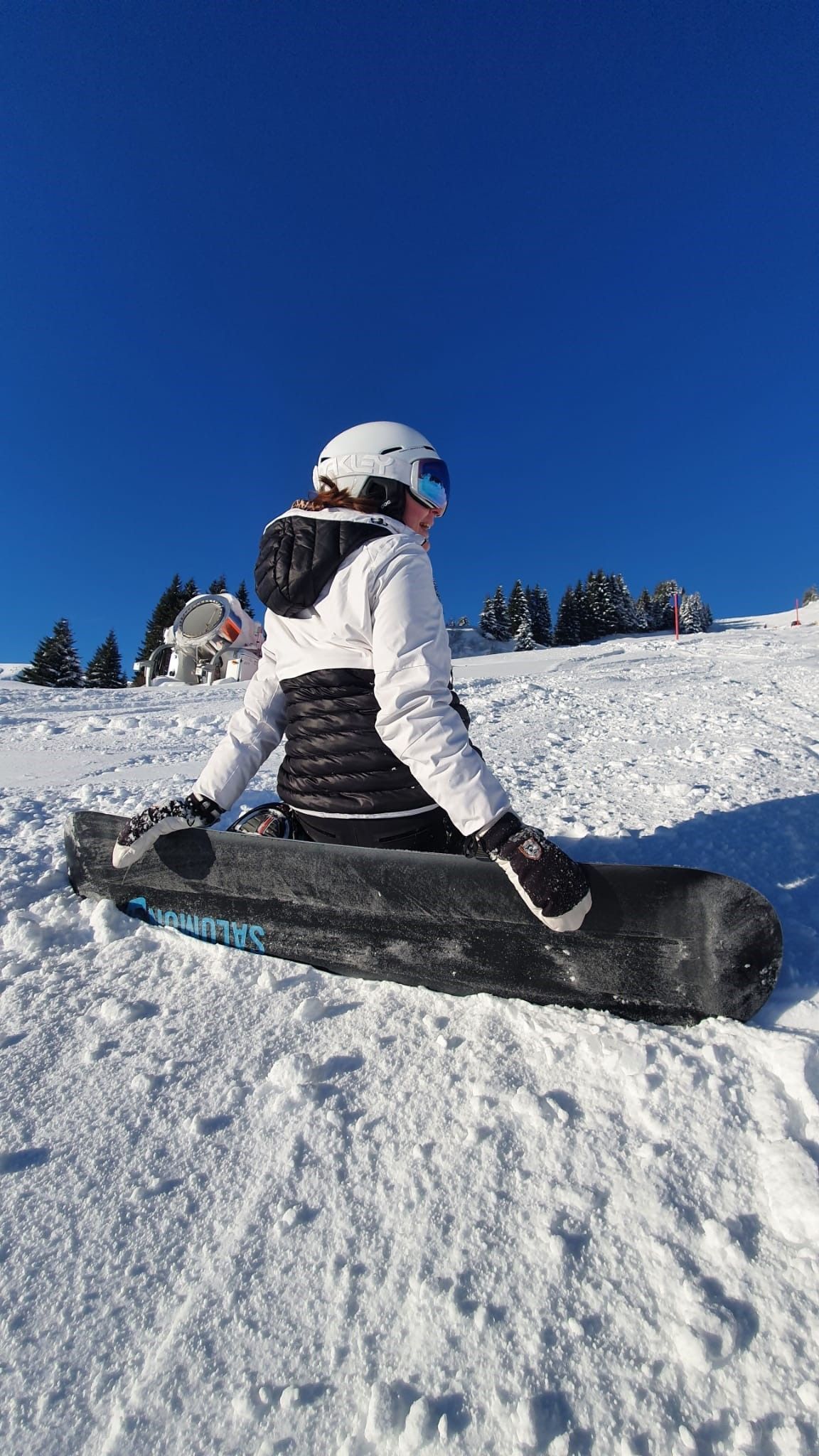 Una persona sentada sobre una tabla de snowboard en una pendiente nevada.