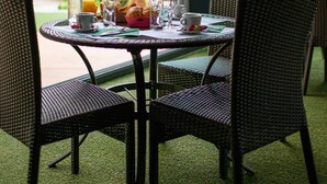 A dining area with wicker chairs and a table set for breakfast. - Camping le Paradis (Talmont-Saint-Hilaire)