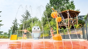 A water play area with a large owl statue, a yellow slide, and a wooden playhouse. - Camping le Paradis (Talmont-Saint-Hilaire)