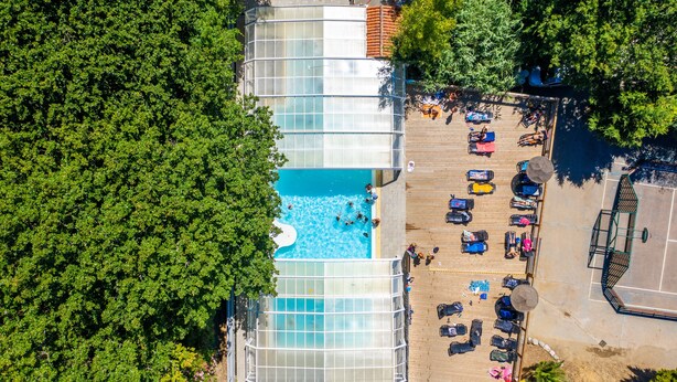 An aerial view of a hotel with a swimming pool surrounded by lounge chairs and umbrellas. - Camping le Paradis (Talmont-Saint-Hilaire)
