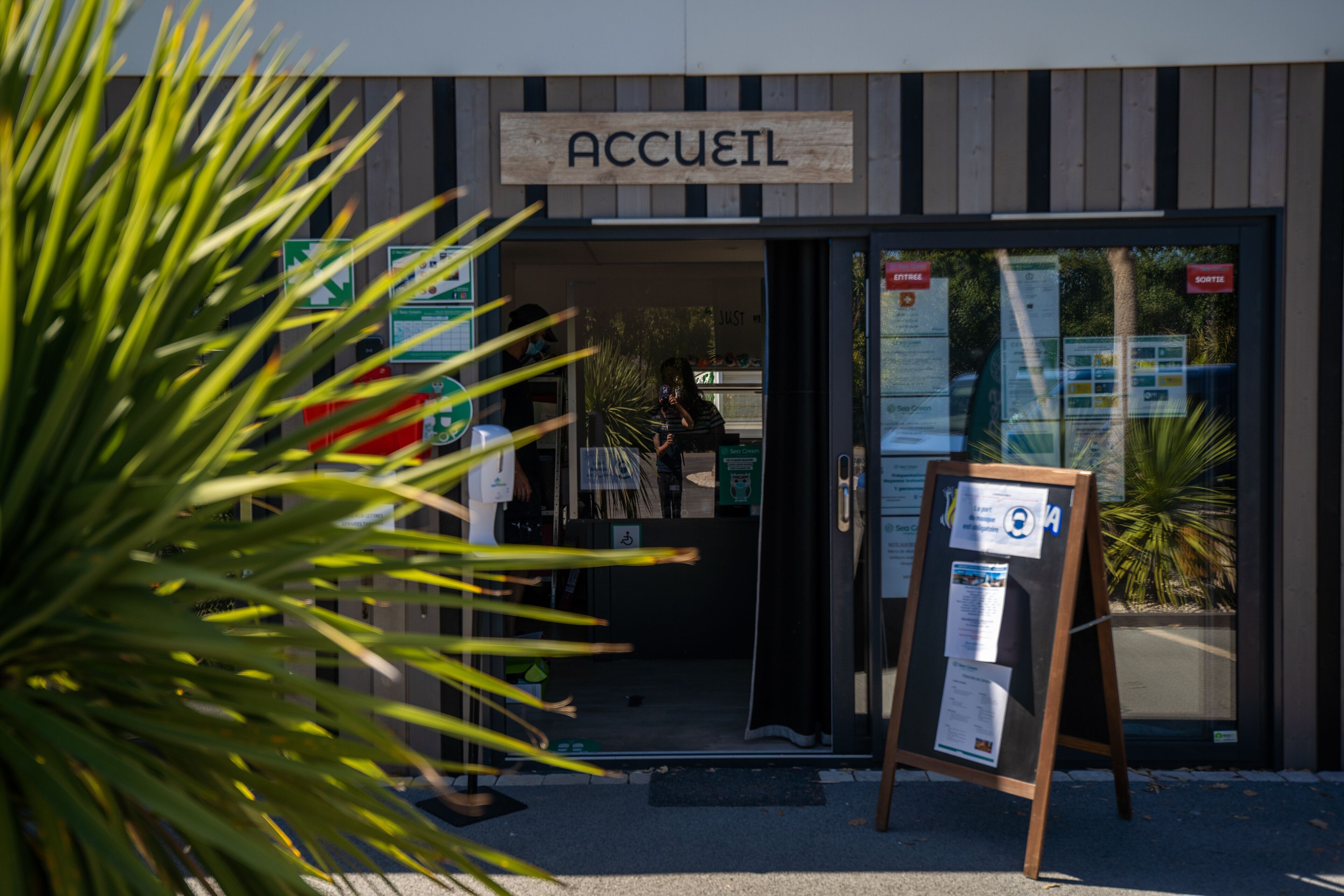 L’entrée d’un hôtel, avec une enseigne indiquant « ACCUEIL » et un comptoir de réception doté d’un panneau.