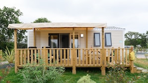 A mobile home with a covered porch, a small deck, and a number '161' on the side. - Camping le Paradis (Talmont-Saint-Hilaire)