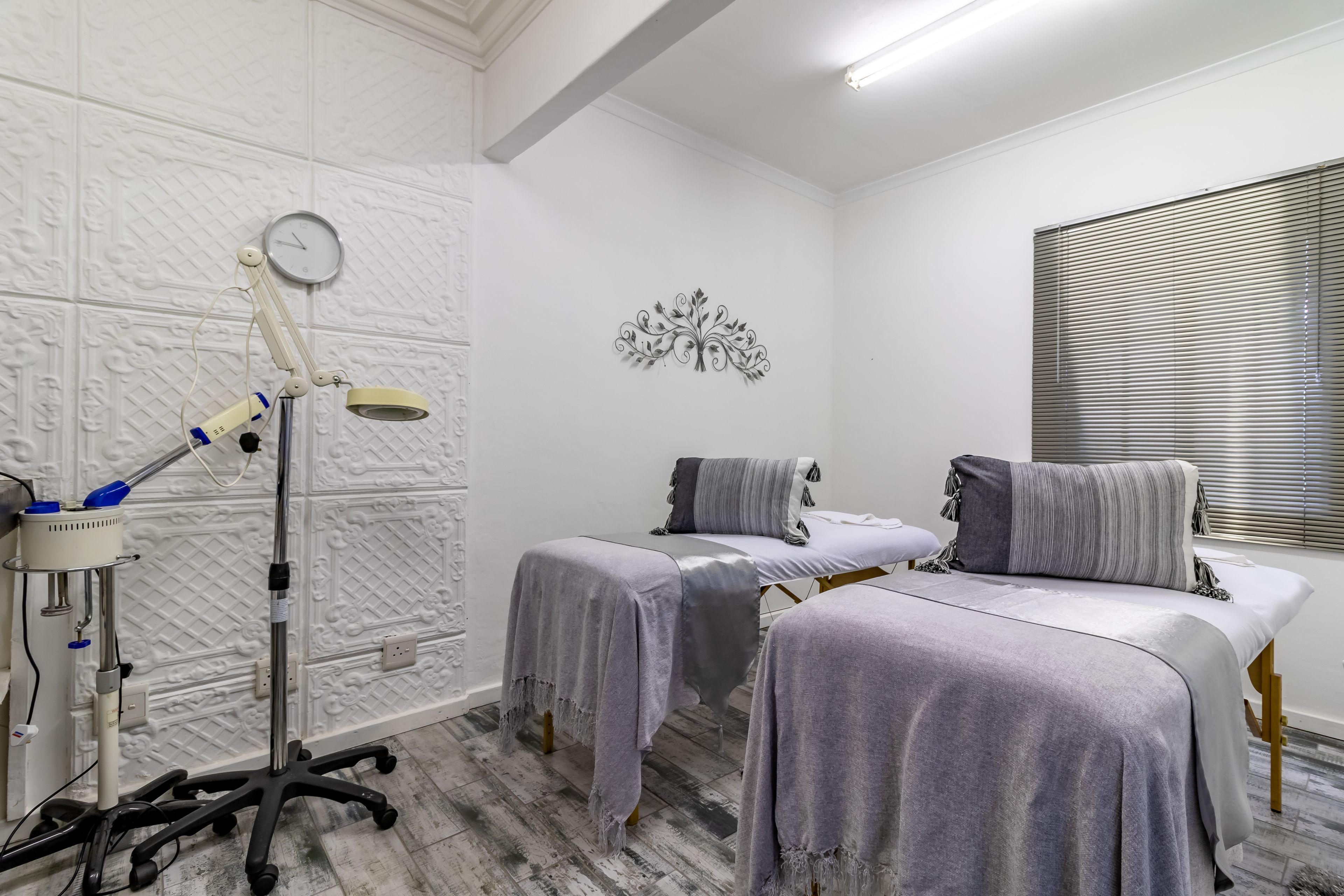 A clinical room with two beds, a medical lamp, and a wall clock.