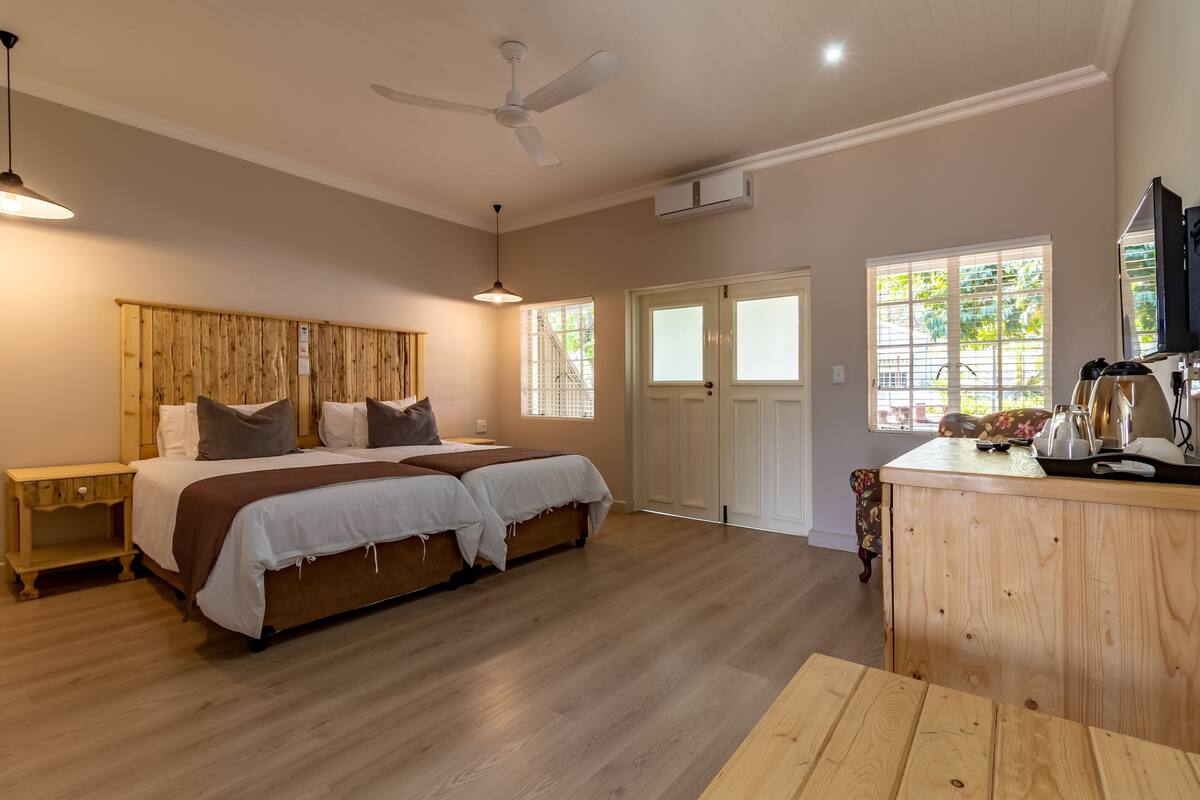A bedroom with a bed, bedside tables, a desk, a chair, a ceiling fan, and a window.