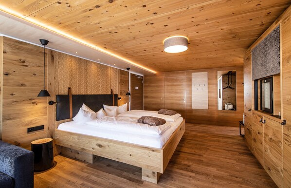 Un dormitorio con paneles de madera, una cama, mesitas de noche y una lámpara colgante.
