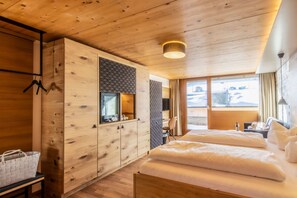 Una habitación con paneles de madera, una cama, un armario, una percha y una ventana con vistas.