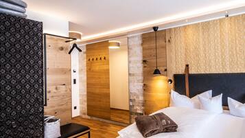 Une chambre d’hôtel moderne avec un grand lit, un banc, un miroir et un mur en bois.
