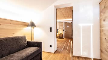 A modern interior with a wooden floor, a grey sofa, and a lamp.