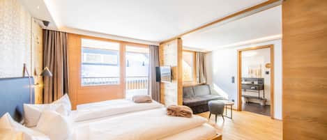 A modern hotel room with a large bed, a desk, a chair, and a television.