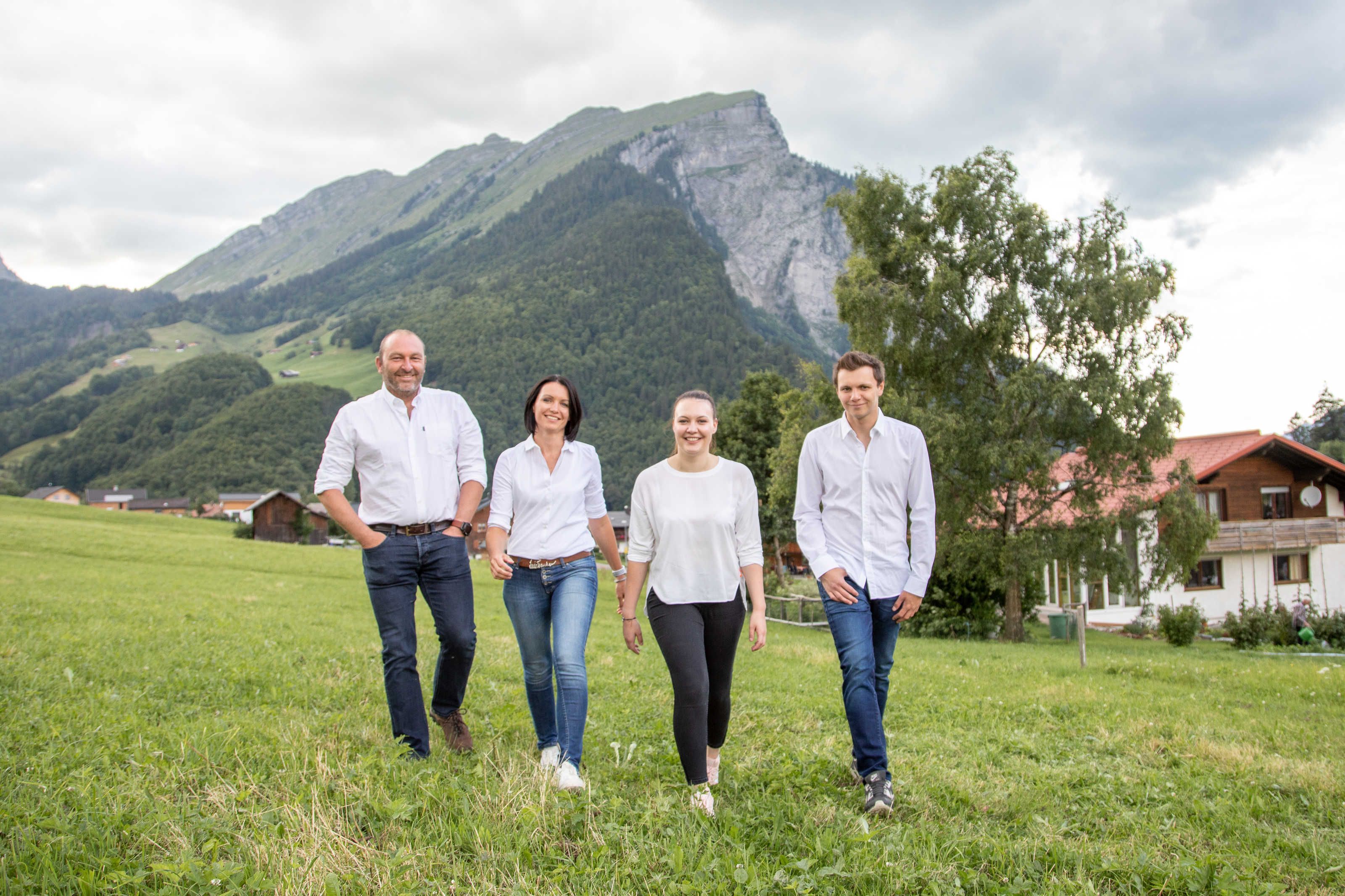 A group of people walking in a grassy field with a mountain in the background.