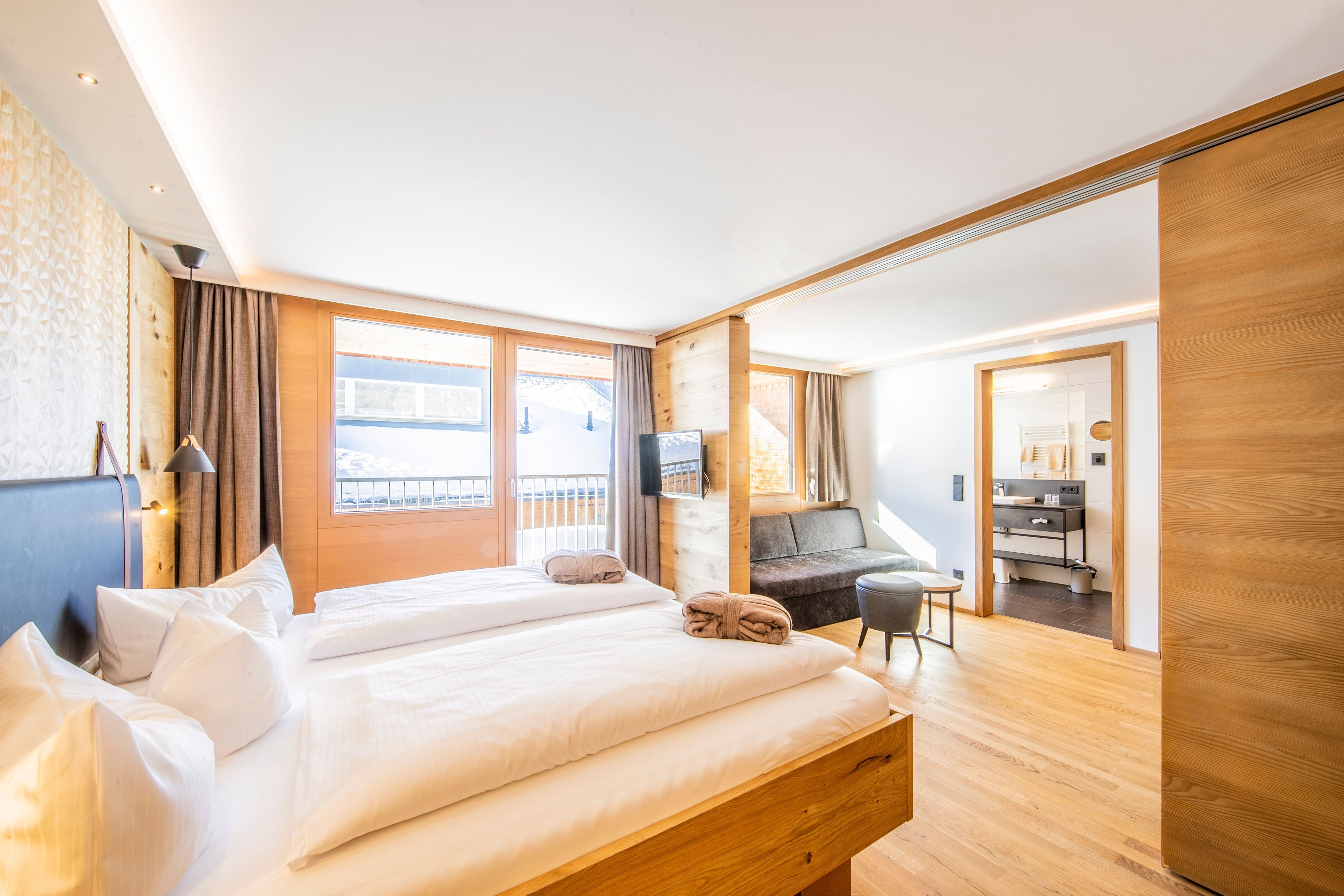 Et moderne hotelværelse med en stor seng, et skrivebord, en stol og et fjernsyn.