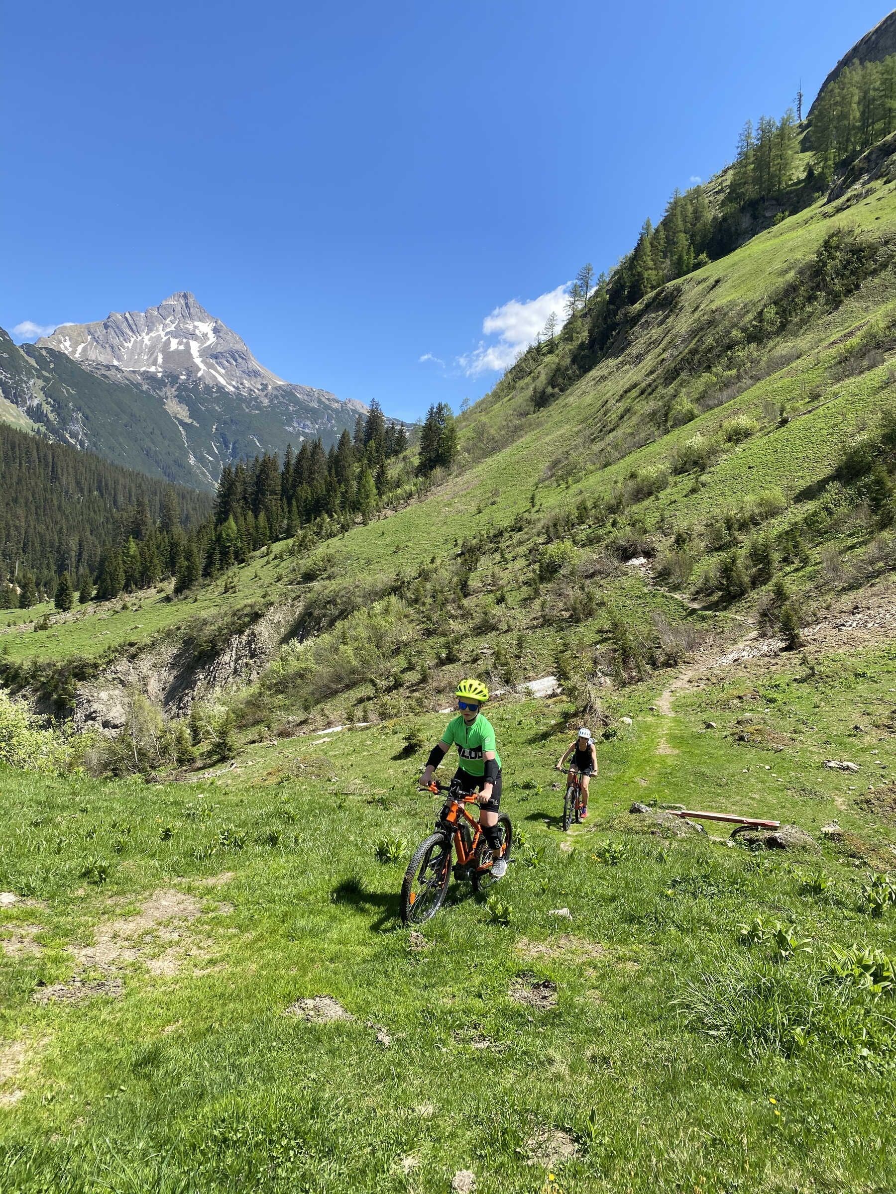 Een mountainbiketrail met een heldere lucht en een berg op de achtergrond.