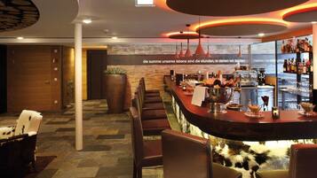 A modern bar area with seating, a counter, and a view of the city.